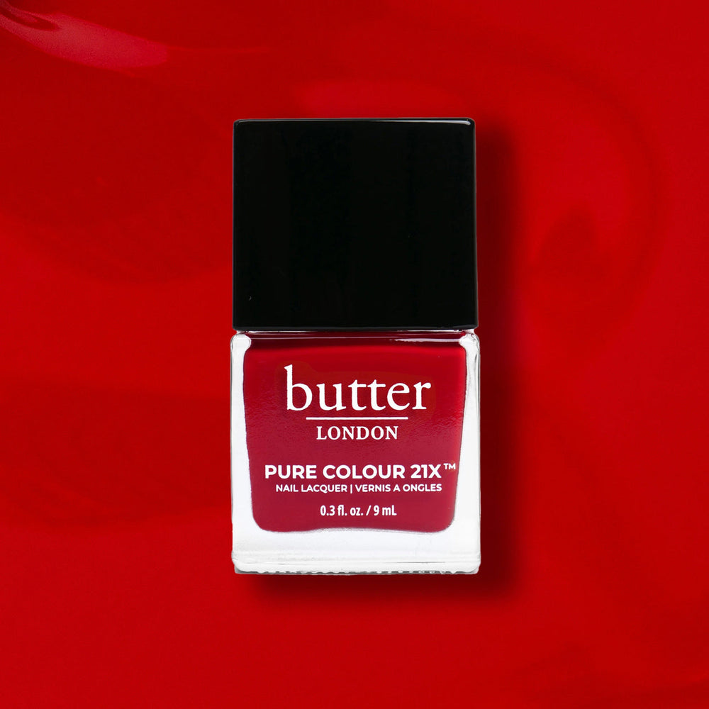 Red nail polish bottle with black cap on a red background, featuring the brand ' butter LONDON'.