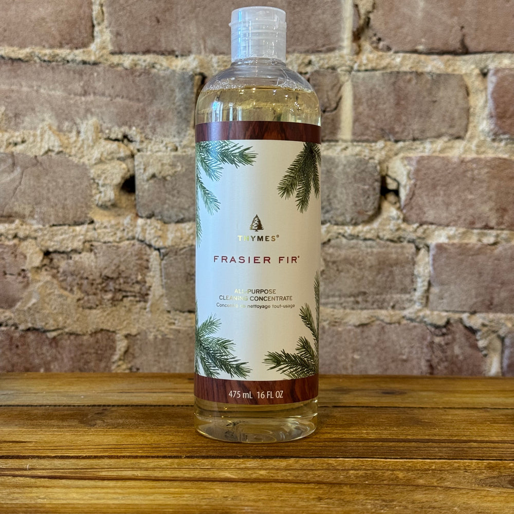 Thymes Frasier Fir all purpose cleaner bottle on a wooden surface with a brick wall background