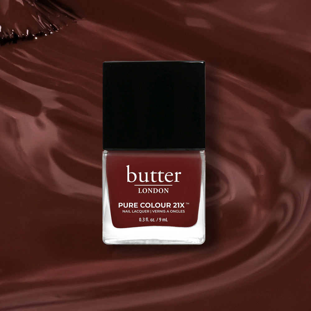 Butter London nail polish bottle on a dark terracotta background