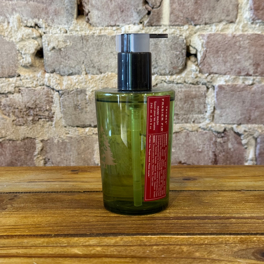 Green bottle with pump dispenser on a wooden surface against a brick wall background