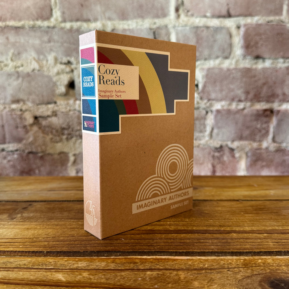 Cardboard box with 'Cozy Reads' and 'Imaginary Authors' branding on a wooden surface with a brick wall background.