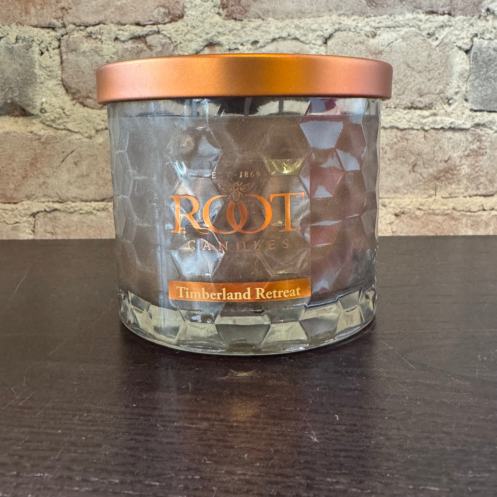 Root Candles Timberland Retreat candle in front of a brick wall