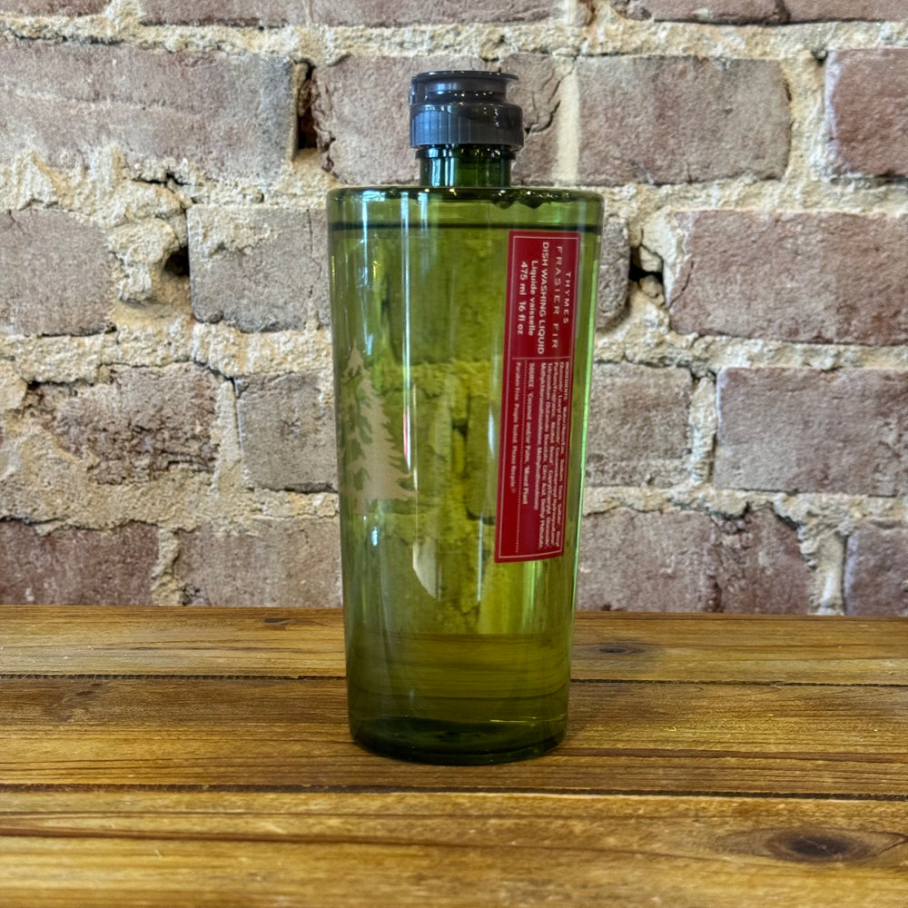 Green bottle with a red label on a wooden surface against a brick wall.
