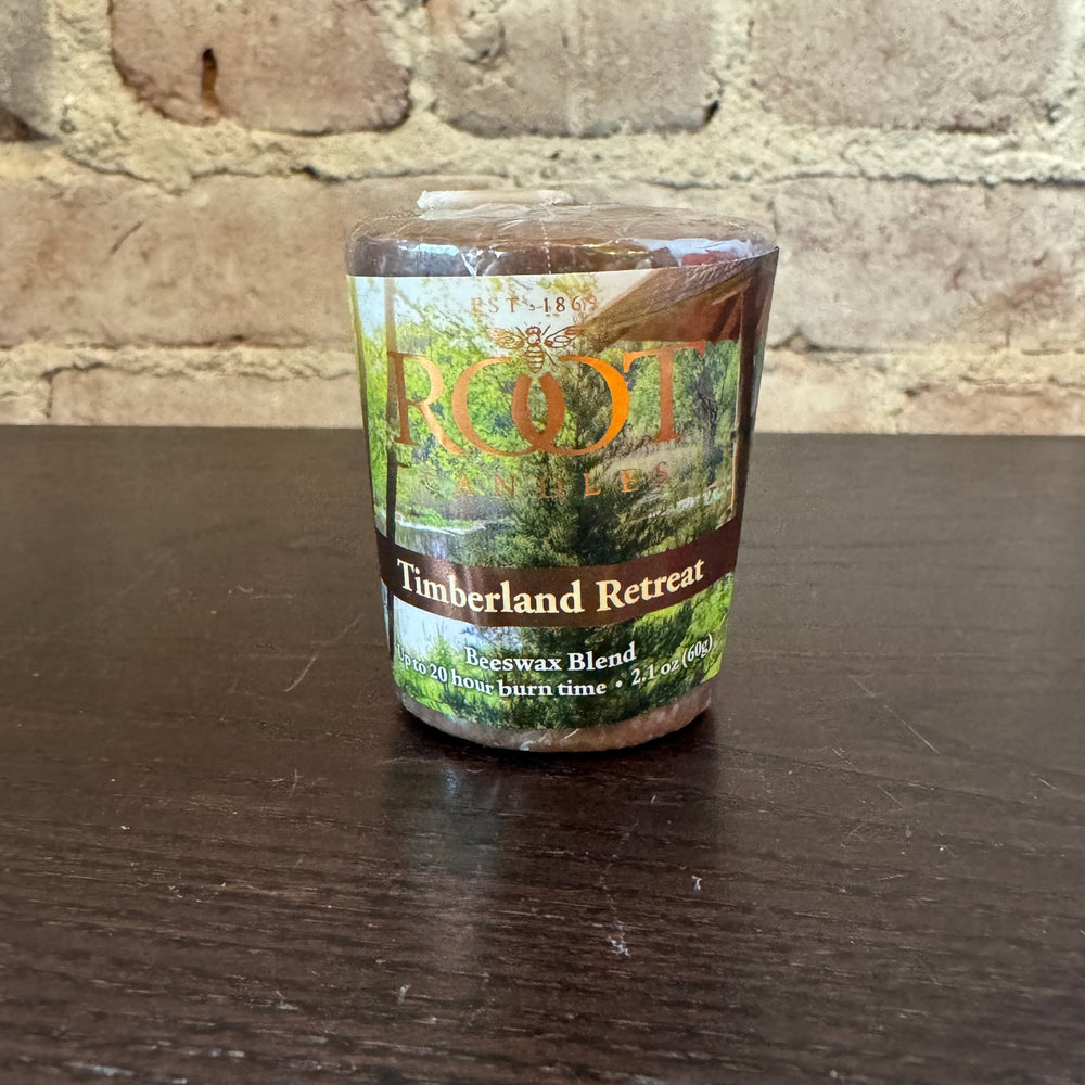 Votive candle with 'Timberland Retreat' label on a wooden surface.