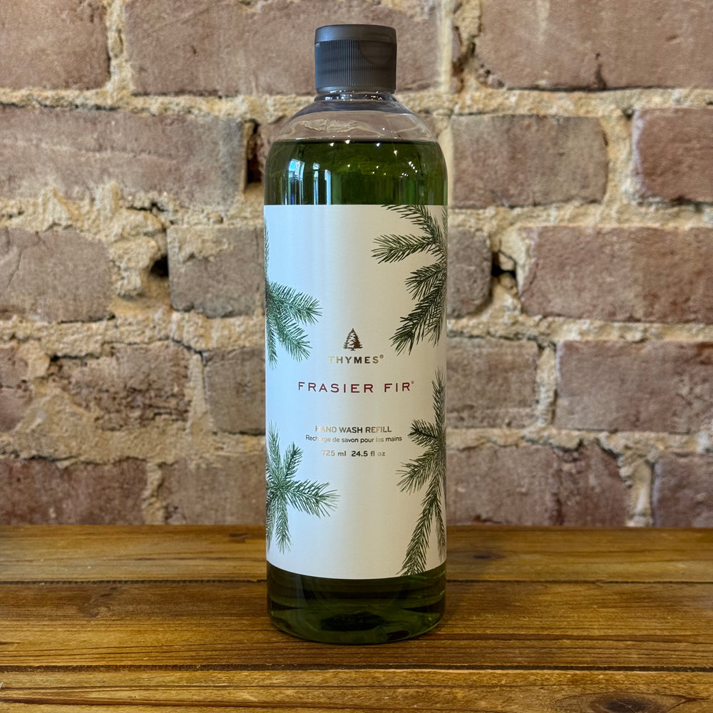 Bottle of Frasier Fir hand wash on a wooden surface with a brick wall background