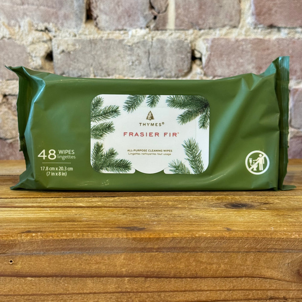 Green package of Thymes Frasier Fir wipes on a wooden surface with a stone wall background